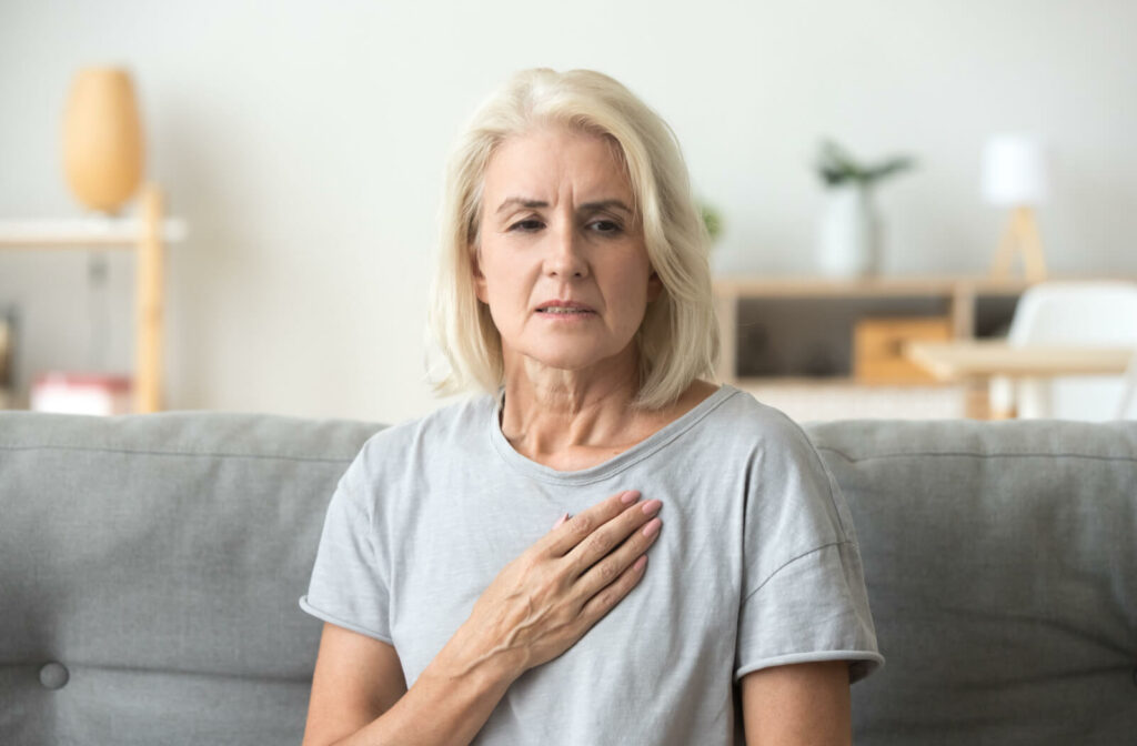 A senior woman puts her hand on her chest as she experiences mild chest pain.