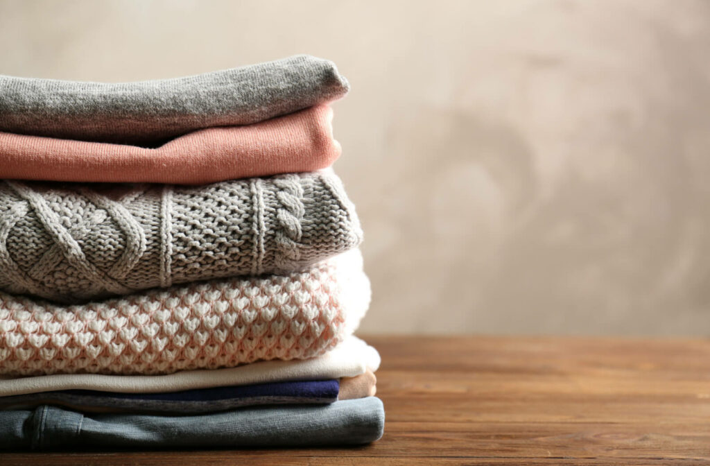 A stack of lightweight cotton shirts for warm weather and cozy sweaters for the cold season.